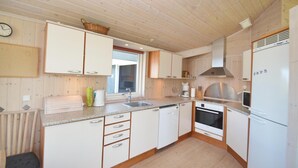 A compact kitchen with wooden cabinets, a sink, a stove, and a refrigerator. - Nice home in Væggerløse with sauna (Væggerløse)