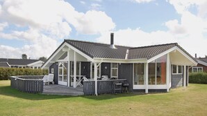 A modern house with a covered patio, a barbecue area, and a large window. - Nice home in Væggerløse with sauna (Væggerløse)