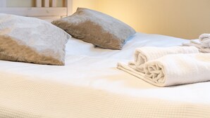 Una cama bien hecha con almohadas y toallas dobladas.