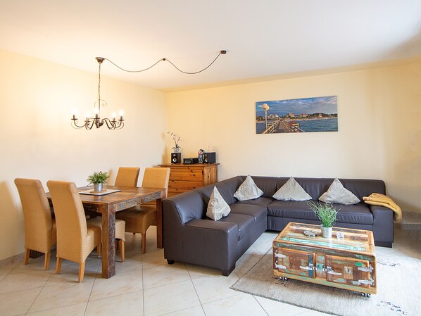Ein Wohnzimmer mit Esstisch, Stühlen, einer Couch und einem Couchtisch.