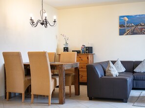 Ein Essbereich mit Holztisch und Stühlen, einer Couch und einem Bild an der Wand.