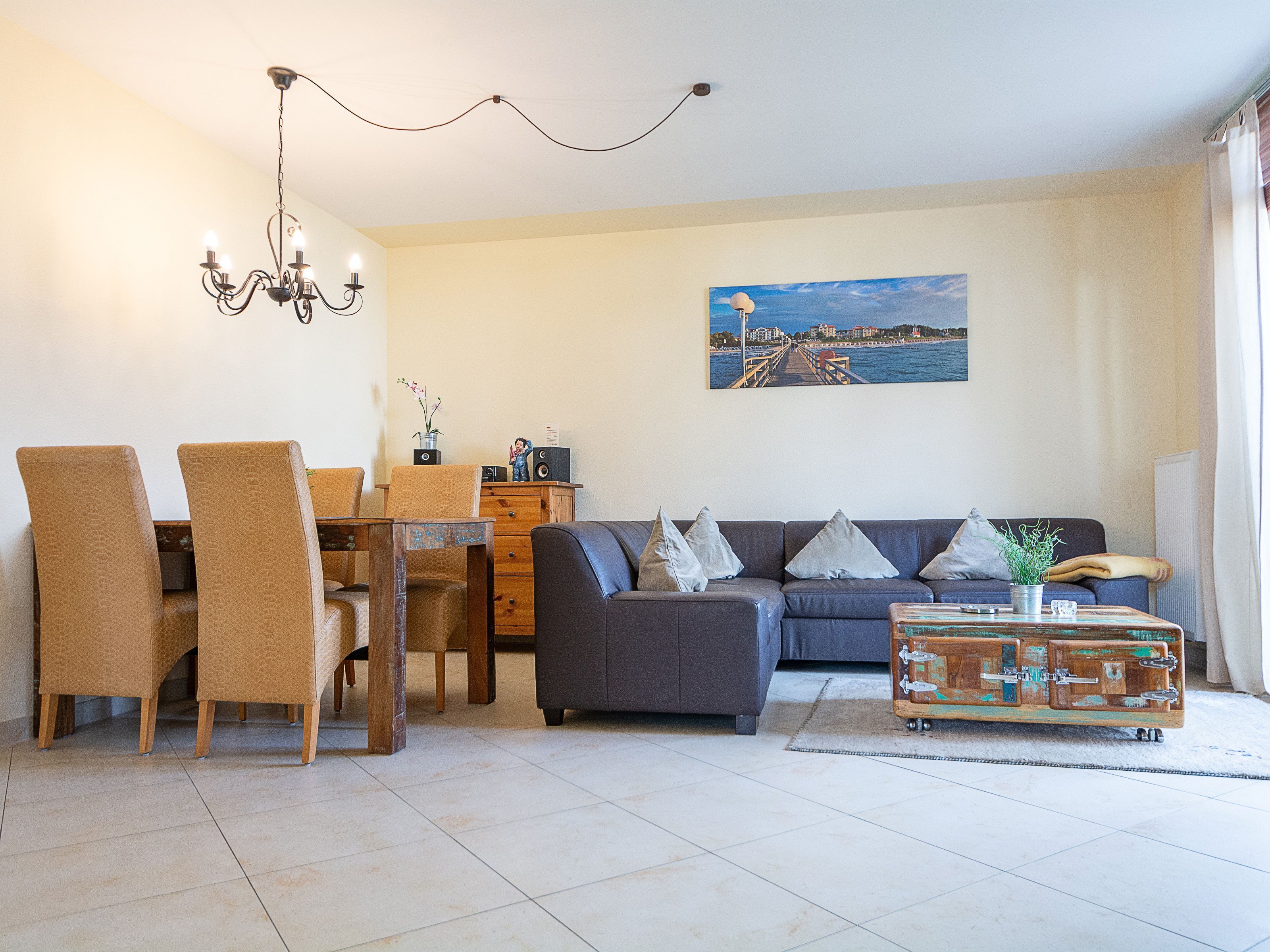 Un salon comprenant un coin repas, un canapé, un lustre et un tableau accroché au mur.