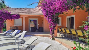 A building with a tiled roof, outdoor seating area with chairs, and a covered patio. - Stunning home in Moriani Plage (Moriani Plage)