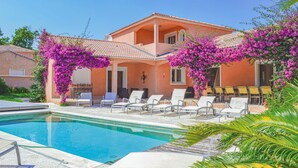 A two-story house with a swimming pool, outdoor seating, and vibrant bougainvillea flowers. - Stunning home in Moriani Plage (Moriani Plage)