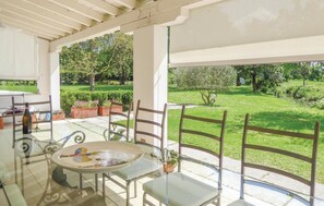 A covered outdoor seating area with a glass table and chairs, overlooking a well-maintained garden with trees and shrubs. - 3 bedroom stunning home in Silea (TV) (Silea (TV))