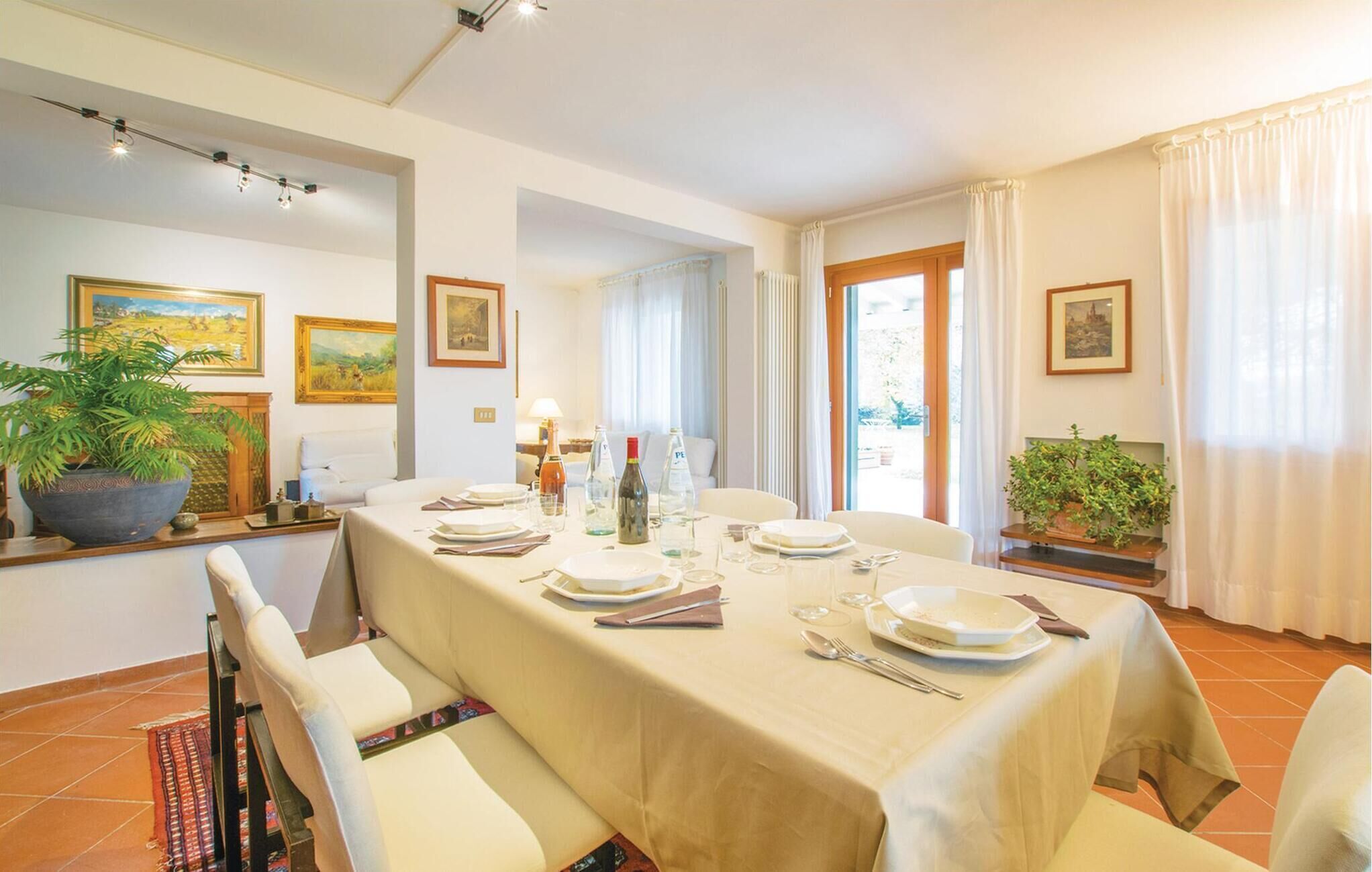 Zona pranzo con tavolo imbandito per quattro, sedie, una pianta in vaso e opere d'arte alle pareti.