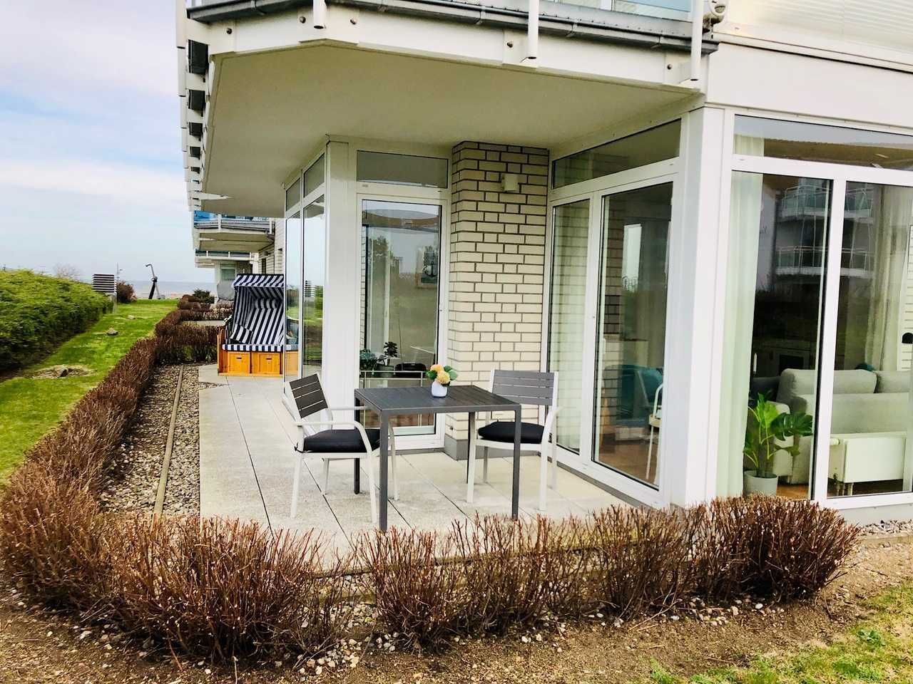 Moderni talo, jossa on patio, jossa on pöytä ja tuolit, tiiliseinä sekä suuret liukuvat lasiovet, jotka johtavat sisätiloihin.