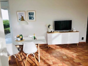 Un salon moderne doté d’un téléviseur à écran plat, de meubles blancs et d’un sol carrelé.