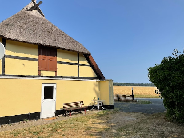 A yellow building with a thatched roof, a door, and a bench outside. - FeHaus 1 - Rügen-Fewo 07 (Dranske auf Rügen)