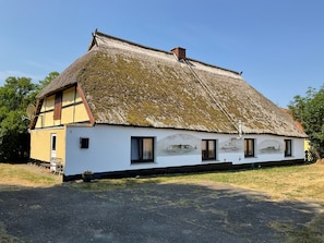A traditional house with a thatched roof, a chimney, and a mural on the side. - FeHaus 1 - Rügen-Fewo 07 (Dranske auf Rügen)