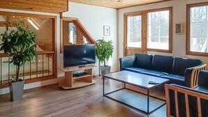 A cozy living room with a TV, sofa, coffee table, and potted plants. - Amazing home in Köpingsvik with sauna (Köpingsvik)