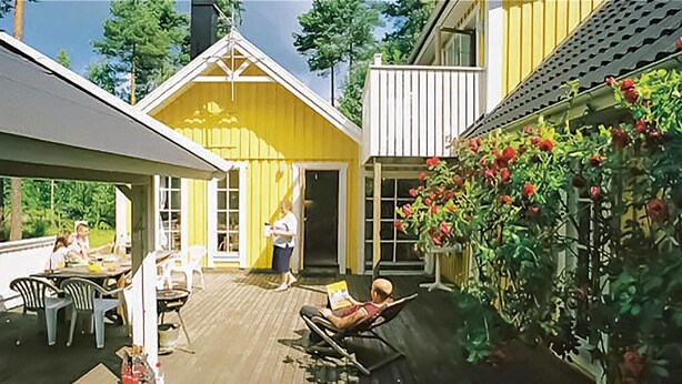 A wooden deck with outdoor furniture, a covered seating area, and a garden with red flowers. - Amazing home in Köpingsvik with sauna (Köpingsvik)