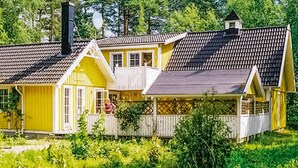 A yellow house with a grey roof, white porch, and a small tower-like structure on the roof. - Amazing home in Köpingsvik with sauna (Köpingsvik)