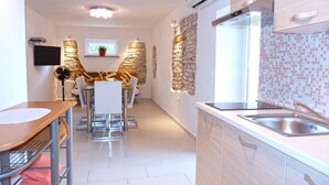 Una cocina moderna con estufa integrada, un lavamanos y una zona de comedor con mesa y sillas.