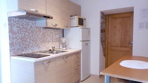 Cocina compacta con microondas, refrigerador y cafetera sobre la encimera.