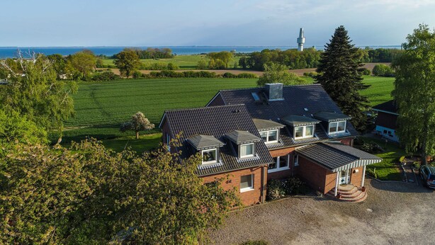 A two-story house with a sloped roof, a visible chimney, and a small garden area. - Lachmöwe, apartment 3 pers. - Vacation farm Kai Hansen (Neustadt in Holstein)