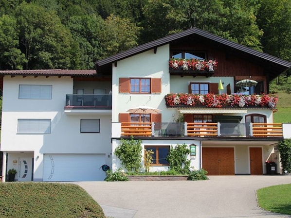 Une maison à deux étages avec un balcon, un garage et un jardin bien entretenu.
