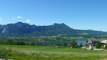 Un paysage rural avec une montagne, un lac et quelques bâtiments.