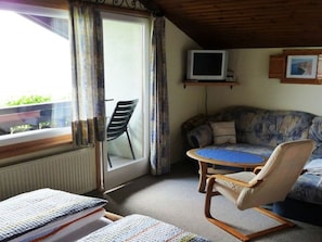 A room with a sofa, a chair, a small table, a television, and a window with curtains. - Guesthouse Ellmauer Annemarie - Apartment Schafbergblick (Tiefgraben)