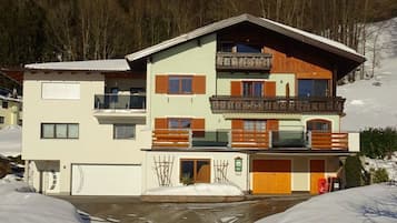 Een meerlaags gebouw met balkons, een garage en een besneeerd landschap.