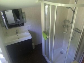 A bathroom with a shower, sink, and mirror.