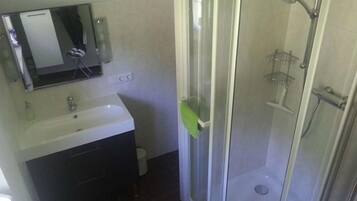 Un bagno con doccia, lavandino e specchio.