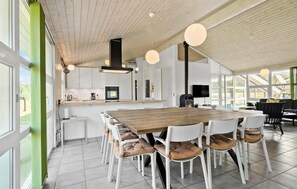 Eine moderne Küche mit einer großen Kochinsel, weißen Schränken und einem Essbereich mit einem Holztisch und weißen Stühlen.