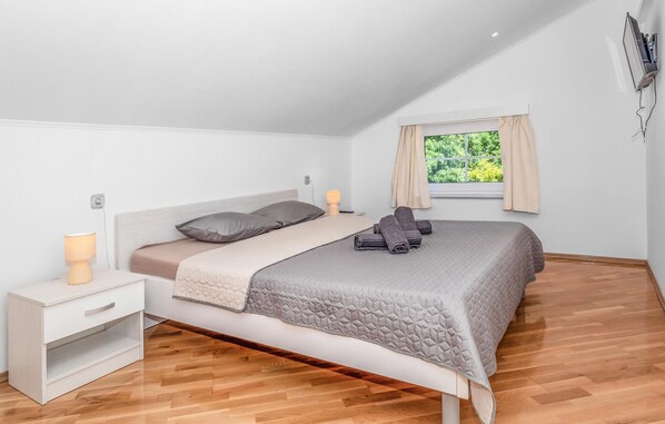 A bedroom with a bed, bedside tables, a lamp, and a window with curtains.