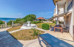 A courtyard with a fountain, a table with chairs, and a view of the sea. - Gorgeous home in Dramalj (Dramalj)