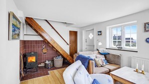 Ein gemütliches Wohnzimmer mit Kamin, Sofa, Couchtisch und Blick ins Freie.