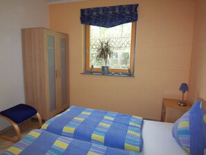 Ein Schlafzimmer mit Bett, Fenster mit Aussicht, Kleiderschrank und Nachttisch.