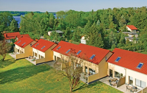 A row of modern, yellow buildings with red roofs, each with a small balcony and a patio area.