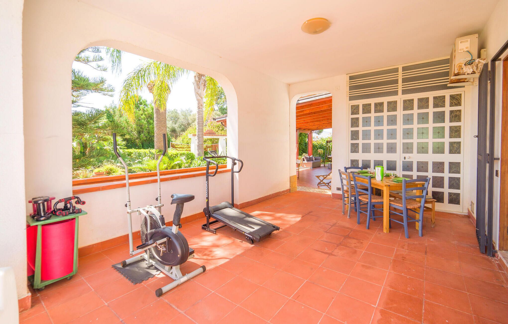 Eine großzügige Terrasse mit Trainingsgeräten, einem Essbereich und Blick ins Freie.