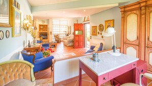 A spacious living room with a fireplace, a dining area, and a kitchen. There are multiple chairs and a table.