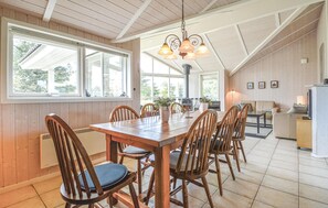 Ein geräumiger Essbereich mit Holztisch und Stühlen, großen Fenstern und einer modernen Küche im Hintergrund.