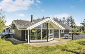 Ein modernes Haus mit einem großen Wintergarten, einem Schornstein und einem Auto auf der Auffahrt.