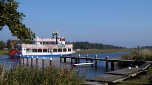 A riverboat docked at a pier with a wooden walkway leading to the dock.