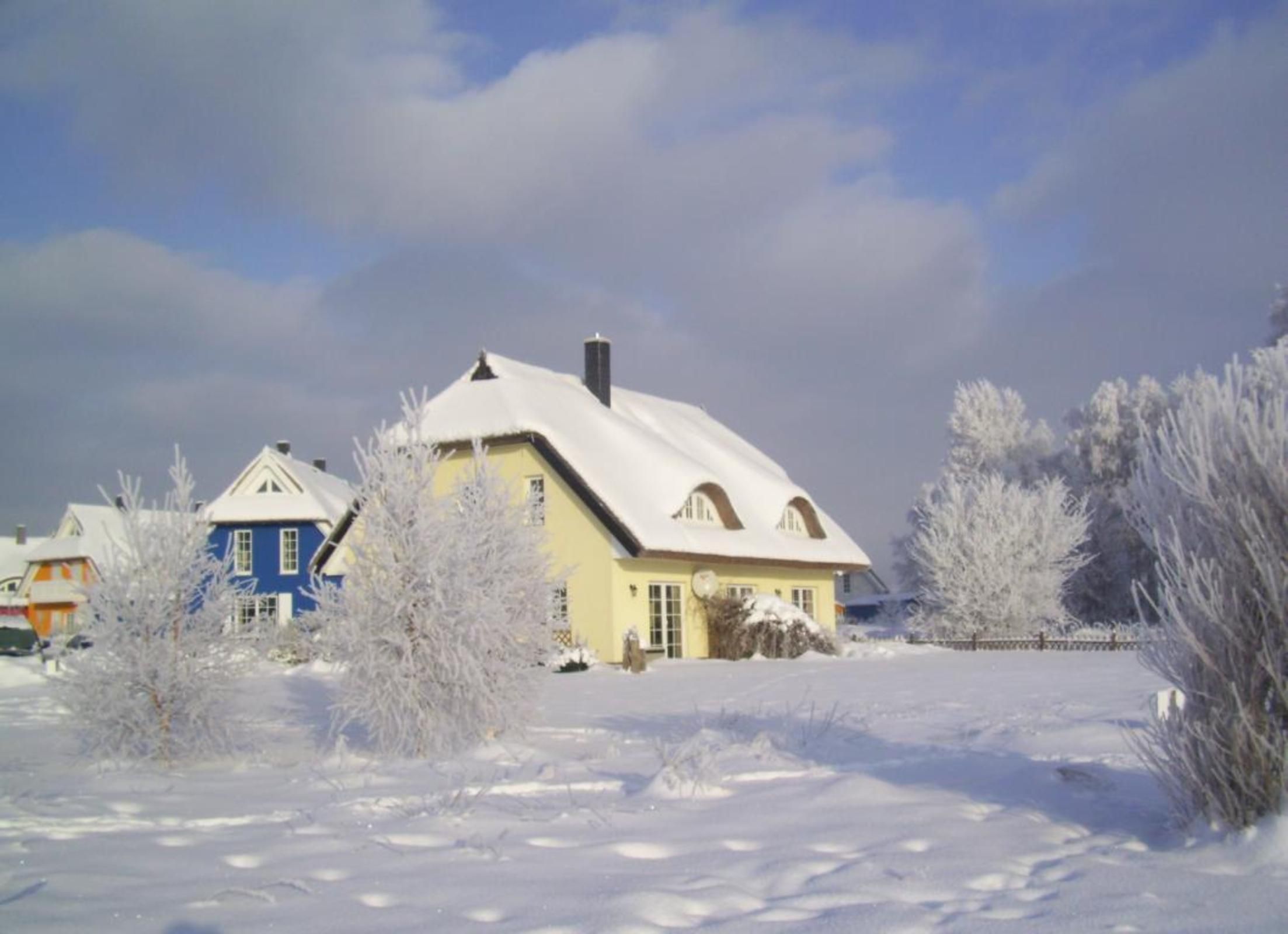 Et sneklædt landskab med huse, heriblandt et gult hus med saddeltag og et blåt hus med en lignende tagkonstruktion.