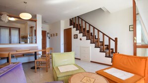 A living room with a wooden staircase, a dining table, and two sofas. - Cozy home in Porto Venere SP with WiFi (Porto Venere SP)
