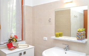 A bathroom with a white sink, a mirror above it, and a window with sheer curtains. - Cozy home in Porto Venere SP with WiFi (Porto Venere SP)