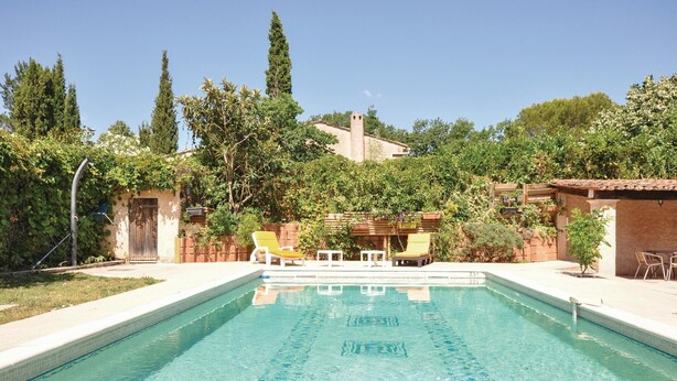 Una piscina rectangular con agua azul cristalina, rodeada por una zona de patio con dos sillas reclinables amarillas y una mesa.