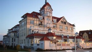 Un hôtel à plusieurs étages, de style architectural traditionnel, doté de balcons et d’une tour centrale.