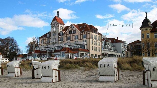 Un immeuble doté d’une tour, portant l’inscription « Balkon App. 222 », et des chaises de plage étiquetées « EH 3 », « EH 5 » et « EH 6 ».