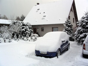 En bostadsbyggnad med ett snötäckt tak och parkerade bilar.