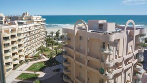 Een hoog hotel met meerdere balkons met uitzicht op een strand.