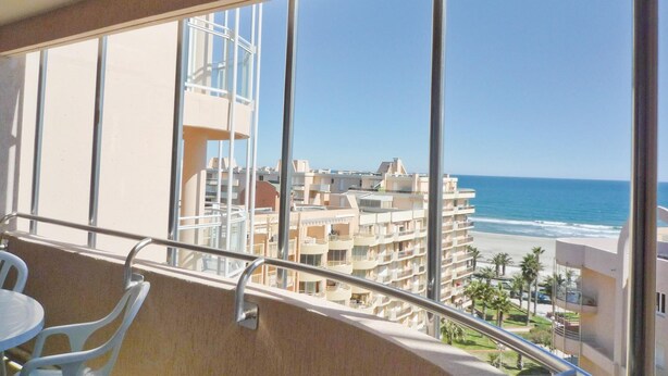 Een balkon met uitzicht op de oceaan en omliggende gebouwen.