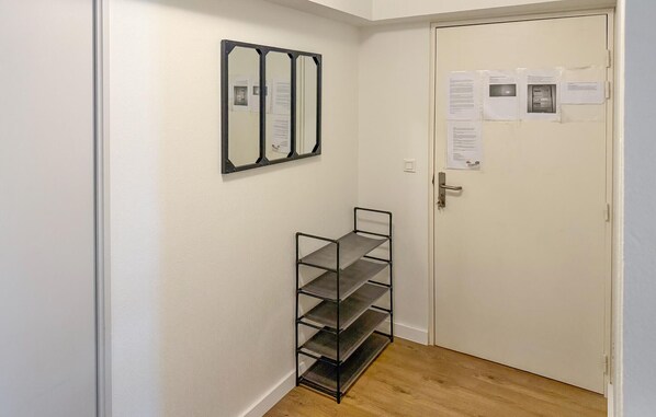 A hallway with a white door, a metal shelf unit, and a wall-mounted mirror. - Lovely apartment in Canet en Roussillon (Canet en Roussillon)