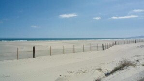 Een zandstrand met een hek en de oceaan op de achtergrond.