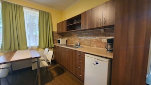 Una cocina compacta con armarios de madera, microondas integrado, cafetera y lavavajillas blanco.