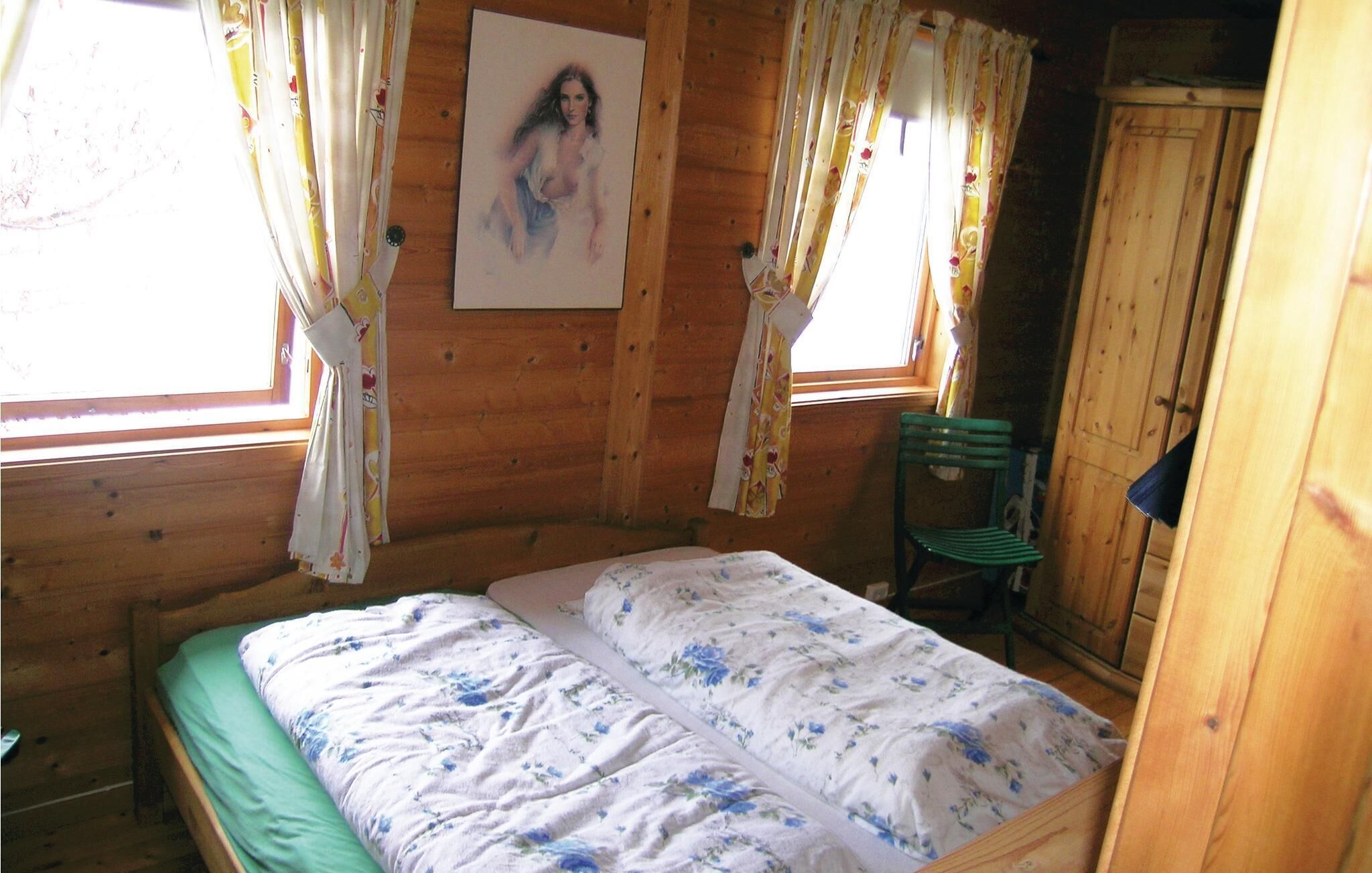 Une pièce de style cabane en bois, avec un lit, une chaise et un tableau accroché au mur.